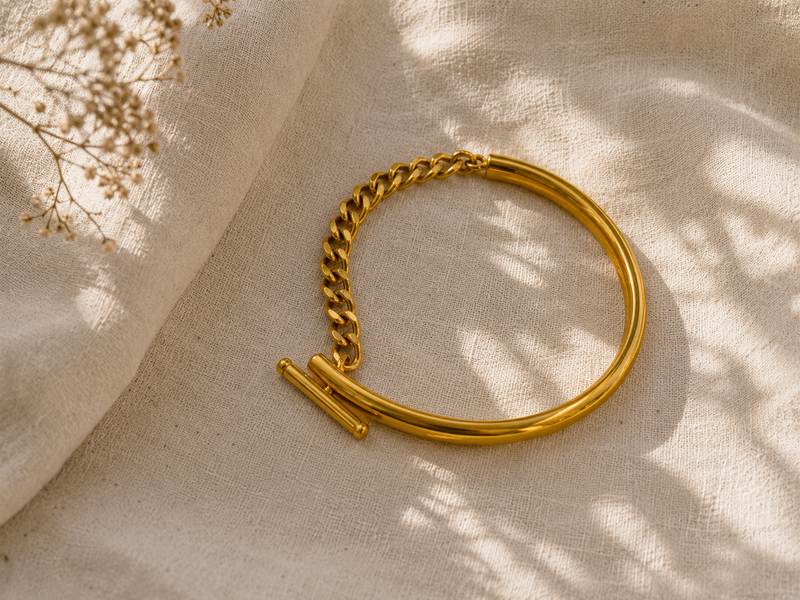 pulsera dorada mediterránea sobre tela de lino y sombras naturales