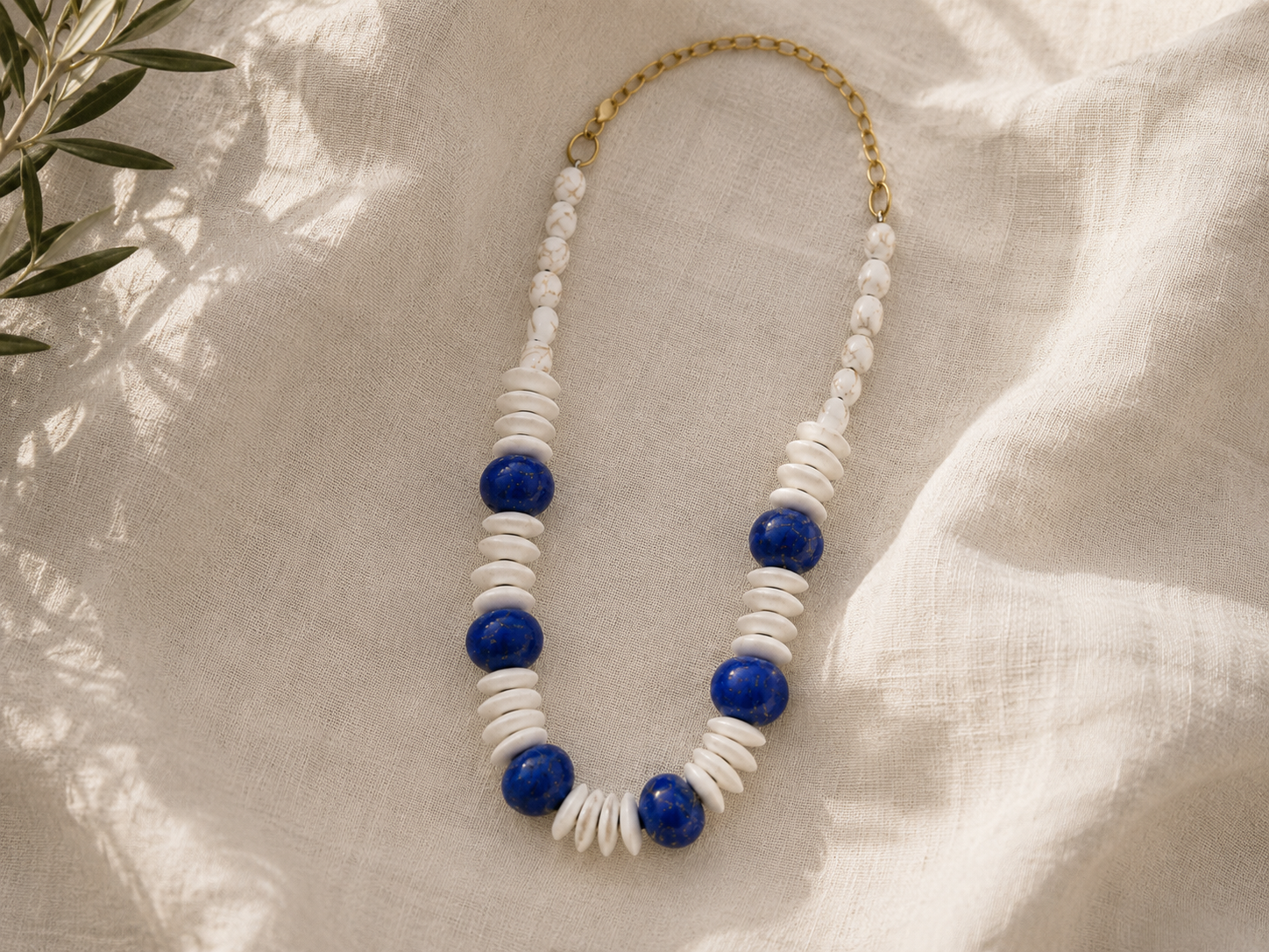 collar mediterráneo de cuentas azules y blancas sobre tela de lino