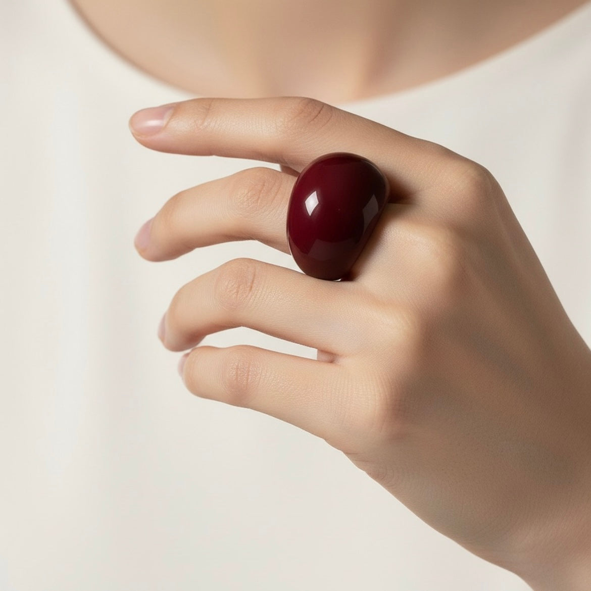 Anillo Burdeos Volumen en mano sobre fondo cálido