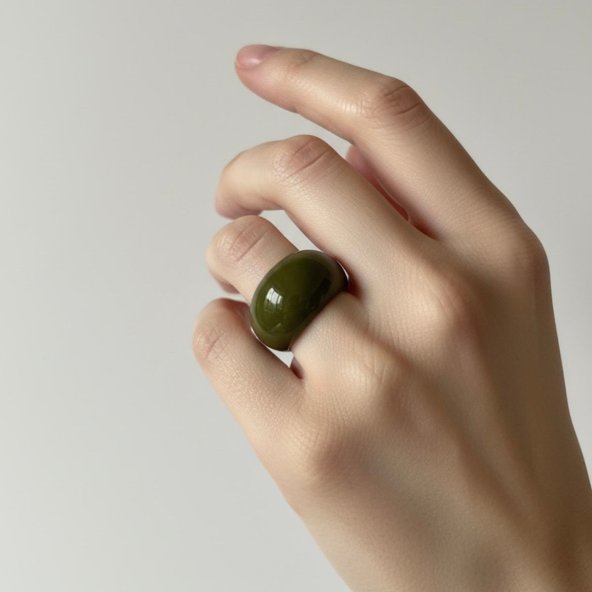 Anillo Verde Volumen en mano sobre fondo cálido